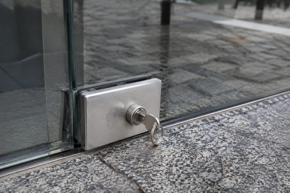 Fechadura de pinça em aço no canto de uma porta de vidro de loja